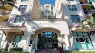 Worthing Place presents an impressive architectural presence defined by its Mediterranean-inspired design. The building's exterior is finished in crisp white stucco and accented with terracotta-toned roofing details, lending it a warm, classical character. A grand arched entryway serves as the focal point of the façade, framed by stately columns and flanked by decorative wall sconces that enhance its welcoming appearance. Large, symmetrically arranged windows span the upper floors, allowing for generous natural light throughout the building's interior levels. The entrance features elegant glass double doors that open into the building, creating a seamless transition from the street to the interior. Decorative tiling and checkerboard accents near the upper floors add a distinctive visual detail that sets the building apart. Lush greenery and seasonal floral arrangements at the base of the entrance contribute to the building's inviting curb appeal. The multi-story structure rises confidently, with a well-proportioned façade that reflects thoughtful architectural planning. Situated at street level with direct access from the sidewalk, Worthing Place combines classic design elements with practical accessibility, making it a notable and recognizable presence in its surrounding environment.