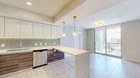 Located at SW First Ave in Miami's vibrant Brickell neighborhood, this 4-bedroom, 2-bathroom unit offers a well-designed layout across a single floor. The contemporary kitchen is a standout feature, showcasing high-gloss white upper cabinets, warm wood-finish lower cabinets, a sleek tile backsplash, stainless steel appliances, and a spacious peninsula with a clean white countertop — all illuminated by stylish pendant lighting. Large-format light tile flooring flows throughout the space, adding a sense of openness and continuity.

The bedrooms are bright and airy, with floor-to-ceiling sliding glass doors opening to views of the Miami skyline and surrounding urban landscape, flooding the rooms with natural light. Two walk-in closets with wire shelving systems provide generous storage options.

Both bathrooms are finished in neutral tones with wood-grain vanities, white countertops, and large-format tile. One bathroom features a tub-shower combination with tiled walls, while the other offers a glass-enclosed walk-in shower. An in-unit laundry area houses a stacked full-size washer and dryer for added convenience. The overall ambiance is clean, modern, and functional — well-suited for urban living in the heart of Miami.