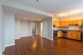 Located at West 14th Street in Chattanooga, Tennessee, this single-floor unit offers a practical and well-organized layout across several distinct spaces. The open-concept living area greets occupants upon entry, featuring rich hardwood-style flooring that extends throughout the main living spaces, neutral gray walls, and a window that allows natural light to fill the room.

The kitchen is positioned adjacent to the living area and is equipped with warm honey-toned wood cabinetry, dark granite-style countertops, and a full suite of stainless steel appliances, including a double-oven range, dishwasher, and sink. The L-shaped counter layout provides functional workspace, and a pass-through design connects the kitchen visually to the broader living space.

A carpeted bedroom offers a quieter, softer environment, complete with a window overlooking the street and neutral toned walls that lend a calm atmosphere. The bathroom features a classic checkered tile floor in muted tones, a window for natural ventilation, and clean white fixtures, maintaining a simple and functional aesthetic throughout.

Track lighting in the kitchen area and recessed lighting in the living space provide well-distributed illumination, contributing to the overall bright and livable character of this Chattanooga residence.