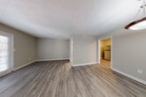 This single-floor unit offers a thoughtfully designed layout with consistent, modern finishes throughout. The open living area features wood-look luxury vinyl plank flooring, neutral-toned walls, and a textured ceiling, creating a clean and versatile backdrop. A pendant light fixture illuminates the entryway, which flows naturally into the main living space. The kitchen is well-equipped with white shaker-style cabinetry, granite countertops, a subway tile backsplash, and stainless steel appliances including a refrigerator, electric range, and dishwasher. Ample upper and lower cabinet storage ensures strong functionality. The bedrooms are carpeted for comfort and each features a ceiling fan with light fixture and a window with blinds that allows natural light to filter in. Two full bathrooms mirror each other in design, each offering white vanity cabinetry topped with granite countertops, a tiled tub-shower combination, wood-look flooring, and a framed mirror. A dedicated dining area adjacent to the entry adds additional versatility to the layout. The cohesive use of neutral tones and updated finishes throughout lends the unit a contemporary, move-in-ready feel.