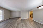 This single-floor unit offers a thoughtfully designed layout with consistent, modern finishes throughout. The open living area features wood-look luxury vinyl plank flooring, neutral-toned walls, and a textured ceiling, creating a clean and versatile backdrop. A pendant light fixture illuminates the entryway, which flows naturally into the main living space. The kitchen is well-equipped with white shaker-style cabinetry, granite countertops, a subway tile backsplash, and stainless steel appliances including a refrigerator, electric range, and dishwasher. Ample upper and lower cabinet storage ensures strong functionality. The bedrooms are carpeted for comfort and each features a ceiling fan with light fixture and a window with blinds that allows natural light to filter in. Two full bathrooms mirror each other in design, each offering white vanity cabinetry topped with granite countertops, a tiled tub-shower combination, wood-look flooring, and a framed mirror. A dedicated dining area adjacent to the entry adds additional versatility to the layout. The cohesive use of neutral tones and updated finishes throughout lends the unit a contemporary, move-in-ready feel.