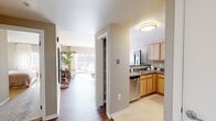 This 1-bedroom, 1-bathroom residence offers a thoughtfully designed single-floor layout that maximizes functionality and comfort. A central hallway connects all rooms, providing a logical and efficient flow throughout the space.

The living room is a bright, welcoming area featuring rich hardwood-style flooring, a two-tone striped accent wall in neutral tones, and a sliding glass door that opens to a private balcony with panoramic urban views. Natural light fills the room generously, enhancing its open and airy feel.

The kitchen is well-equipped with light maple cabinetry, dark countertops, stainless steel appliances including a dishwasher, electric range, and refrigerator, and tile flooring. Ample upper and lower cabinet storage ensures strong practicality.

The bedroom is a comfortable retreat featuring plush carpeting, large windows with blinds, and a bold red accent wall that adds a striking focal point. A dedicated closet provides organized storage space.

The bathroom is finished with marble-look tile flooring, a full soaking tub with shower, and warm neutral wall tones.

Rounding out the layout is a hallway closet, offering additional storage. The overall palette of warm beiges, whites, and grays gives the space a cohesive, modern residential aesthetic.