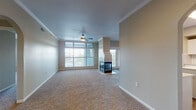 This single-floor residence offers a thoughtfully designed layout that balances open communal areas with comfortable private spaces. The living room serves as the heart of the home, showcasing a striking tile-surround, glass-front fireplace as a central focal point, paired with plush carpeting, crown molding, and a ceiling fan. Large windows flood the space with natural light and provide outdoor views, while an adjacent carpeted area with an arched entryway offers additional flexibility for dining or a secondary sitting area.

The kitchen is well-equipped for everyday living, featuring white shaker-style cabinetry, subway tile backsplash, light quartz countertops, and a central island with a built-in sink. Stainless steel appliances—including a refrigerator, range, and microwave—complete the functional layout, which also benefits from wood-look flooring and ample cabinetry storage.

The bedrooms are carpeted and bright, each with a ceiling fan and window with outdoor views. Two bathrooms serve the residence: one features a double-sink vanity with a tub/shower combination, while the second offers a single vanity with a separate shower stall. Both bathrooms include white cabinetry and wood-look flooring, maintaining a cohesive, clean aesthetic throughout the home.