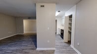 Located at 1303 Ocala Rd in Tallahassee, Florida, this single-floor residence offers a clean, functional layout with a neutral color palette throughout. Wood-look plank flooring runs through the main living and kitchen areas, providing a cohesive and easy-to-maintain surface, while carpeting adds warmth to the bedrooms.

The galley-style kitchen is well-appointed with white cabinetry, light countertops, a stainless steel sink, and a full suite of black appliances including a refrigerator, range, and dishwasher. Open shelving near the kitchen entry adds convenient storage and display space.

The main living area is generously sized and filled with natural light, featuring a large sliding glass door that opens to a view of mature trees, creating a peaceful, nature-connected ambiance. A secondary window further enhances the flow of natural light into the space.

A central hallway, lit by wall-mounted sconces, connects the living areas to the private quarters. Bedrooms are carpeted and offer dedicated closet space with built-in shelving and hanging rods. The layout also includes additional built-in shelving and a utility closet, maximizing storage throughout. Textured ceilings and crisp white trim complete the interior details, giving the space a tidy, well-maintained appearance.