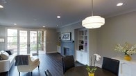 This thoughtfully designed single-floor residence exudes a refined, contemporary aesthetic. The main living and dining area is anchored by a handsome tiled fireplace framed by custom built-in shelving and cabinetry — offering both display space and convenient storage. Dark hardwood floors run throughout, providing a rich contrast against the neutral gray walls and crisp white trim and crown molding.

The dining area is illuminated by an elegant tiered drum pendant light that serves as a focal point overhead, complementing the dark furnishings below. Recessed lighting throughout the ceiling ensures the space is well-lit from every angle.

Natural light pours in through full-length French doors that lead to a private outdoor balcony, where views of surrounding greenery create a seamless connection between indoor comfort and the outdoors. The balcony extends the living space and provides an inviting area for outdoor relaxation.

The overall ambiance is polished and welcoming, with a careful balance of dark and light tones that create visual depth throughout. Built-in shelving flanking the fireplace adds architectural character while keeping the space functional and organized, making this a practical yet elegant living environment.