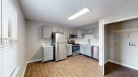This single-floor residence in Louisville, KY offers a well-organized layout with a practical and cohesive design. The kitchen serves as a functional centerpiece, outfitted with gray shaker-style cabinetry, white countertops, and a full suite of stainless steel appliances including a refrigerator, range, microwave, and dishwasher. Wood-look plank flooring runs throughout the kitchen and main living areas, contributing a warm, clean aesthetic. The open connection between the kitchen and living area allows for an easy flow, with the living space receiving natural light through a window fitted with horizontal blinds and a ceiling fan providing overhead illumination and air circulation. The bedrooms are carpeted and neutrally toned, with ceiling fans in each room. The primary bedroom features double closets with full-length hanging rods, while the secondary bedroom includes a single closet with a rod and shelf. The bathroom is neatly appointed with a gray vanity, white countertop, framed mirror, lighted vanity fixture, wood-look flooring, and a full tub-shower combination. Neutral gray walls and white trim are consistent throughout, creating a clean and move-in ready environment.