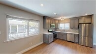 This single-story home in Santa Rosa, California offers a thoughtfully updated interior defined by a consistent, contemporary aesthetic. Warm wood-style flooring flows seamlessly throughout the entire space, complemented by neutral gray walls and clean white baseboards that create a bright, cohesive feel.

The kitchen serves as a standout feature, showcasing gray raised-panel cabinetry with ample storage, light countertops, and a subtle tile backsplash. A full suite of stainless steel appliances — including a gas range, built-in microwave, dishwasher, and refrigerator — provides modern functionality. Multiple windows allow generous natural light to fill the kitchen, offering views of the surrounding neighborhood greenery.

The remaining rooms are generously proportioned, each benefiting from recessed lighting and windows that frame outdoor views of mature trees and the surrounding area. The open layout, as seen in the floor plan, includes multiple rooms well-suited for flexible use, along with access to additional spaces such as a laundry area. The overall design is clean and move-in ready, presenting a well-maintained interior well-suited to comfortable everyday living in the heart of Santa Rosa.