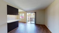 Located at 1515 Broadway in El Cajon, California, this single-floor unit offers a well-organized layout with consistent wood-look flooring running throughout every room, contributing to a cohesive and clean aesthetic. The open living and dining area is bright and airy, benefiting from natural light streaming through a large sliding glass door that opens onto a private balcony with outdoor views — an ideal spot for relaxing or enjoying the Southern California climate. Adjacent to the living area, the kitchen is thoughtfully equipped with dark espresso cabinetry, a full-size refrigerator, an electric range, and overhead lighting with a recessed ceiling detail that adds a subtle architectural touch. A white countertop peninsula separates the kitchen from the living space, providing both functionality and visual definition. The unit includes two well-proportioned bedrooms, each featuring wood-look flooring and windows that admit generous natural light. The primary bedroom includes a closet and an en-suite vanity area with dark cabinetry and a wide mirror. A full bathroom serves the unit with a dark-cabinet vanity, white countertop, and wood-look flooring. The overall palette of warm neutrals and dark cabinetry accents creates a practical and inviting living environment.