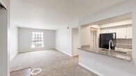 Located at 4301 Falcon Creek Blvd in Indianapolis, Indiana, this 2-bedroom, 1-bathroom residence offers a well-organized single-floor layout with a clean, neutral aesthetic throughout. The open-concept design connects the living area to the kitchen via a pass-through granite countertop bar, creating a functional and visually connected common space. The kitchen is well-appointed with white cabinetry, subway tile backsplash, granite countertops, and black appliances including a refrigerator and range with overhead ventilation. A tray ceiling detail adds subtle architectural interest to the kitchen area. Soft carpeting extends through the living area, hallway, and both bedrooms, contributing to a warm and comfortable feel. The primary bedroom is generously sized, featuring a sliding closet with built-in shelving, and a window that invites natural light. The second bedroom also includes a closet and a window with outdoor views. A connecting hallway with additional closet storage links the rooms efficiently. The bathroom features wood-look flooring, a granite-topped vanity, and a shower-tub combination. The overall palette of soft grays and whites gives the space a fresh, move-in ready appearance.
