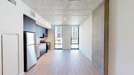 Located at 625 North 2nd Avenue in the heart of downtown Phoenix, this modern studio presents a thoughtfully designed open-concept layout that seamlessly integrates the living, dining, and kitchen areas into one cohesive space. A defining architectural feature is the exposed concrete ceiling, which lends an industrial-chic character throughout, complemented by light wood-style flooring that adds warmth and continuity underfoot.

Floor-to-ceiling windows flood the living area with abundant natural light and frame views of the surrounding Phoenix skyline, creating a bright and airy ambiance. The kitchen is outfitted with dark, flat-panel cabinetry extending to the ceiling, stainless steel appliances including a refrigerator, gas range, microwave, and dishwasher, paired with a clean white tile backsplash and light countertops for a sleek, contemporary finish.

A hallway leads to the well-appointed bathroom, which features a backlit vanity mirror, undermount sink, light wood cabinetry with matte black hardware, and tiled flooring. The unit also includes a dedicated closet and an in-unit laundry area, adding practical convenience. Clean white walls throughout keep the space feeling open and versatile, making this a well-equipped urban retreat in downtown Phoenix.