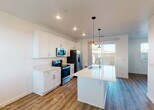 This well-appointed two-story home offers a clean, modern aesthetic throughout, with thoughtful design details visible in every room. The heart of the home is a stylish kitchen featuring crisp white cabinetry, quartz countertops, and a full suite of stainless steel appliances including a French door refrigerator, electric range, and microwave. A central island with a built-in sink and elegant pendant lighting serves as a functional focal point, while durable wood-look flooring and a sliding glass door leading to an outdoor space add to the kitchen's appeal.

The upper floor hosts generously sized bedrooms finished with plush carpet, ceiling fans, and ample natural light from multiple windows with blinds. The primary bedroom includes a walk-in closet and is complemented by a private en-suite bathroom featuring a glass-enclosed shower, white vanity with quartz countertops, and stylish gooseneck lighting. A secondary full bathroom offers a shower-tub combo, white vanity, and coordinating fixtures. A carpeted hallway connects the upper-level rooms, maintaining a cohesive and welcoming flow. Throughout the home, a neutral color palette and recessed lighting create a bright, clean atmosphere ideal for modern living.