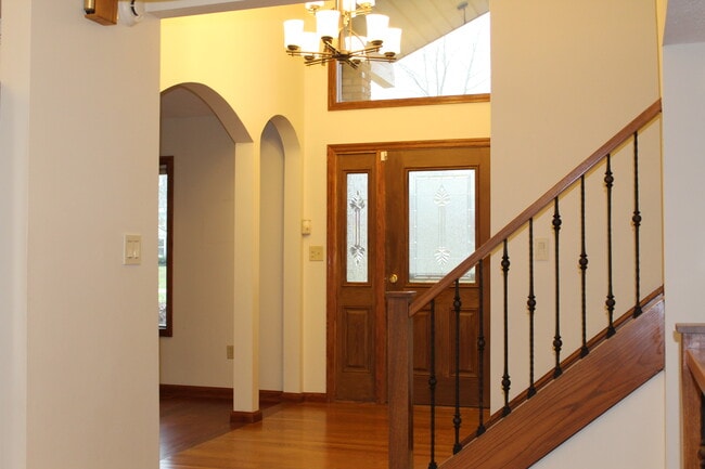 Inviting foyer with hardwood floors, glass front door, and decorative iron staircase railing. - 6235 Sunnywood Dr