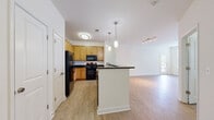 Located at 700 Acropolis Way in Frederick, Maryland, this single-story residence offers a clean, functional layout highlighted by consistent wood-look flooring throughout. The open-concept kitchen serves as a central feature, equipped with warm honey-toned cabinetry, dark granite-style countertops, and a full suite of black appliances including a refrigerator, range, and built-in microwave. A peninsula island with pendant lighting overhead provides additional prep space and creates a natural transition into the adjoining living area. The living space is generously proportioned, featuring track lighting and a glass-paned exterior door that allows natural light to fill the room.

The bedrooms are bright and well-sized, each featuring the same wood-look flooring, neutral white walls, and windows overlooking the surrounding outdoor environment. Double closet doors in one bedroom offer practical storage solutions. The bathrooms maintain a consistent design aesthetic with warm wood-toned vanity cabinetry and light countertops. Both bathrooms include accessibility features such as grab bars, with one offering a walk-in shower stall. Open shelving near one bathroom provides convenient additional storage. Overall, the space presents a straightforward, accessible, and well-lit living environment.