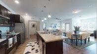 This well-designed single-floor residence offers a thoughtfully laid-out open-concept floor plan that seamlessly connects the kitchen, dining, and living areas. The kitchen is a standout feature, anchored by a large island with granite-style countertops, dark espresso cabinetry extending to the ceiling, stainless steel appliances including a refrigerator, microwave, and electric range, and warm wood-look flooring. A built-in desk nook provides a convenient workspace just off the kitchen. Pendant lighting and recessed ceiling lights illuminate the space effectively.

The living area is bright and welcoming, with natural light streaming through multiple windows fitted with blinds. A ceiling fan adds comfort, and the generous layout accommodates both a sitting and dining area with ease.

The bedrooms offer plush carpeting, ceiling fans, and ample natural light from multiple windows, creating calm and restful retreats. The bathrooms are finished with matching dark cabinetry, granite-style countertops, wood-look flooring, and include both a walk-in shower option and a standard tub-shower combination. A dedicated in-unit laundry room houses a full-size washer and dryer with overhead shelving for added storage. Throughout, the space maintains a cohesive, contemporary aesthetic with neutral tones and quality finishes.