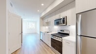 Located at 1445 Town Center Dr in Chula Vista, CA, this thoughtfully designed single-floor unit offers a clean, contemporary aesthetic throughout its well-utilized floor plan. The kitchen serves as a central highlight, featuring sleek white cabinetry extending to the ceiling, white quartz countertops, a classic subway tile backsplash, and a full suite of stainless steel appliances including a gas range, over-the-range microwave, dishwasher, and refrigerator. Light wood-look flooring runs through the main living and kitchen areas, lending warmth and continuity to the space. The living area benefits from natural light streaming in through windows that frame views of the surrounding community. Bedrooms are finished with plush neutral carpeting and feature windows with exterior views, providing a comfortable and restful atmosphere. A spacious walk-in closet with multi-tiered shelving and hanging rods offers generous storage. The bathroom is outfitted with wood-look flooring, a soaking tub with tiled surround, built-in shelving, a single vanity with a large mirror, and recessed lighting. A clean, light-filled hallway connects the rooms, completing this well-appointed and efficiently designed residence.