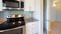 Located in Ocala, Florida, this two-floor home offers a well-designed layout with architectural character and quality finishes throughout. The main level centers around an open living and kitchen area, where soaring vaulted ceilings create a dramatic sense of height and volume. The kitchen is outfitted with crisp white cabinetry, granite countertops, a glass tile backsplash, stainless steel appliances including a range and over-the-range microwave, and a breakfast bar that connects seamlessly to the living area. Pendant and track lighting illuminate both spaces. The bathrooms feature matching granite vanity tops, white cabinetry, tile flooring, and a tub-shower combination, with one bathroom offering access to a walk-in closet. Bedrooms are carpeted and bright, each equipped with a ceiling fan and windows that invite natural light and outdoor views of the surrounding greenery. The upper level includes additional carpeted spaces with vaulted and angled ceilings, a staircase landing with an arched window, and open loft-style areas that offer flexible use. Throughout the home, warm neutral tones, consistent finishes, and thoughtful detailing create a cohesive and comfortable living environment.