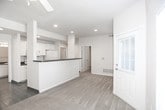 This single-floor residence offers a practical and cohesive layout throughout its various living spaces. The main living area is generously proportioned, featuring wall-to-wall neutral carpet, multiple windows with blinds that invite abundant natural light, a ceiling fan with integrated lighting, and direct access to an exterior door. The warm, neutral wall tones carry consistently throughout the home, creating a unified aesthetic.

The kitchen is equipped with white cabinetry, white appliances including a microwave and refrigerator, and recessed lighting. A peninsula with a dark countertop provides additional prep space and defines the boundary between the kitchen and the adjacent living area, which transitions from tile to carpet flooring.

The bedrooms are carpeted and well-sized, each featuring ceiling fans and windows that allow natural light. One bedroom includes a vaulted ceiling, adding a sense of openness, while another offers direct access to a dedicated laundry room housing a full-size washer and dryer with wire shelving above.

Both bathrooms are finished with dark countertops, white vanity cabinetry, large mirrors, and tile flooring. One bathroom includes a shower, while the other offers additional towel bar storage. The overall ambiance of the home is clean, functional, and move-in ready.
