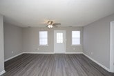 This two-floor residential space offers a practical and well-maintained interior with a clean, neutral aesthetic throughout. The rooms are finished with soft gray walls and crisp white baseboards, creating a calm and cohesive look across the home. Textured popcorn ceilings add a classic touch, while flush-mount light fixtures provide steady overhead illumination in key areas.

Flooring varies by room, with dark hardwood-style planks lending a modern, grounded feel to certain spaces, while plush carpeting in adjoining rooms adds warmth and comfort underfoot. A ceiling fan is visible in one of the connected rooms, offering both air circulation and supplemental lighting.

A distinctive architectural detail is a small interior pass-through window with a white frame, recessed into the wall between rooms — a functional and charming feature that adds character to the layout. The open doorway between rooms promotes a connected flow and allows natural sightlines across the interior.

Overall, the space presents a straightforward and functional layout spread across two floors, with consistent finishes that provide a move-in ready, livable environment suitable for a variety of needs.
