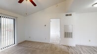 This single-floor residence offers a well-organized layout with a variety of functional spaces designed for comfortable everyday living. The main living area stands out with its dramatic vaulted ceiling and a ceiling fan, creating an open, airy atmosphere. Light-toned carpet covers much of the living and bedroom areas, while wood-look hard flooring is featured at transitional spaces. A sliding glass door fitted with vertical blinds allows natural light to fill the living area and provides outdoor access.

The galley-style kitchen is efficiently designed with warm wood cabinetry lining both sides, offering generous storage. Light countertops and a double stainless steel sink complement the space, which also includes a white electric range, refrigerator, and dishwasher. A window at the end of the kitchen brings in additional natural light.

The bedrooms are carpeted and feature ceiling fans, with windows dressed in horizontal blinds to manage light and privacy. One bedroom benefits from a vaulted ceiling, mirroring the grandeur of the main living area. The bathroom includes a clean, white tiled tub-shower combination with chrome fixtures. Throughout the space, the neutral white walls and consistent finishes create a cohesive, move-in ready environment.