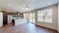Located at 3600 Cliff Oaks Dr in Corinth, TX, this two-story home offers three bedrooms and three full bathrooms across two well-organized floors. The ground floor features an open-concept living, dining, and kitchen area bathed in natural light from large windows and sliding glass doors that lead to a private patio overlooking a landscaped yard. Rich hardwood-style flooring flows throughout the main living space, complemented by a ceiling fan and recessed lighting overhead. The kitchen is a standout, boasting dark espresso cabinetry, a geometric tile backsplash, stainless steel appliances including a refrigerator, microwave, and range, and a generous white quartz island with an undermount sink and stylish pendant lighting. The attached garage offers ample space with an automatic opener. Upstairs, the primary bedroom is a comfortable retreat featuring plush carpet, a ceiling fan, recessed lighting, and direct access to its own bathroom. Additional bedrooms are well-sized with ample closet space, including walk-in closets with built-in shelving. The bathrooms are finished with dark vanities and wood-look flooring. A dedicated laundry area and hallway complete the upper level, making this home as functional as it is stylish.