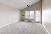 Located at 5741 Amberbrooke Arch in Virginia Beach, Virginia, this single-floor, two-bedroom, one-bathroom home offers a well-organized layout across a comfortable footprint. The open-concept kitchen is a functional highlight, featuring warm wood cabinetry, dark granite countertops, stainless steel appliances including a range, microwave, and refrigerator, and light tile flooring. A peninsula with pendant lighting connects the kitchen to the living area, creating a natural flow ideal for everyday living and entertaining. The living room is notably spacious, enhanced by vaulted ceilings that lend an airy, open feel. A large window and an exterior door fill the room with natural light and provide outdoor access. Soft, neutral carpeting runs throughout the living and bedroom areas. The primary bedroom is generously sized, offering ample space for furnishings, and is brightened by a window with views of the surrounding neighborhood. The second bedroom, also carpeted, includes a window for natural light. The bathroom is well-appointed with a wood vanity, tile flooring, and a full tub-shower combination. A connecting hallway ties all rooms together for a cohesive and practical living experience.