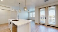 Located at 4353 E Elliot Rd in Gilbert, AZ, this thoughtfully designed single-story residence offers 1 bedroom and 2 full bathrooms within a well-utilized floor plan. The open-concept kitchen and living area serves as the heart of the home, featuring light wood-style flooring, recessed lighting, and a ceiling fan. The kitchen is a standout space, showcasing crisp white shaker cabinetry extending to the ceiling, a decorative tile backsplash, stainless steel appliances including a refrigerator, range, and microwave, and a central island with a white quartz countertop, undermount sink, and pull-down faucet. Gold geometric pendant lights add a modern, upscale touch. The living area extends naturally from the kitchen, bathed in natural light from multiple windows and a glass exterior door offering outdoor views. The bedroom features plush carpeting, a ceiling fan, and ample natural light from multiple windows. The bathrooms are finished with white cabinetry, quartz countertops, and light wood-style flooring. Additional conveniences include a dedicated closet, in-unit laundry, and built-in shelving. The overall aesthetic is clean, bright, and contemporary throughout.