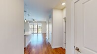 This thoughtfully designed single-story unit offers a spacious and functional layout across a generous floor area. The open-concept living and kitchen space serves as the heart of the unit, featuring rich hardwood flooring, recessed lighting, and a ceiling fan that extends seamlessly toward a wall of floor-to-ceiling sliding glass doors opening onto a private balcony, filling the space with natural light and outdoor views.

The kitchen is well-equipped with dark-stained wood cabinetry, a tile backsplash, stainless steel appliances including a gas range, microwave, and refrigerator, and a large central island with a white countertop and undermount sink. Pendant lighting above the island adds a polished finishing touch.

The bedroom is a spacious retreat with plush carpeting, a ceiling fan, and a bright window overlooking the surrounding landscape. A conveniently located stacked washer and dryer unit is accessible directly from the bedroom area, adding practical functionality.

The bathroom is elegantly finished with large-format marble-style tile flooring, a dual-sink vanity featuring granite countertops and gray cabinetry, a wide mirror, and a marble-tiled walk-in shower. An adjacent walk-in closet provides ample storage with built-in shelving.