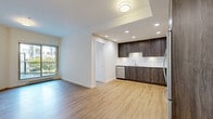 Located at 809 Village Dr in Port Coquitlam, BC, this well-designed two-bedroom, one-bathroom residence offers a thoughtfully organized single-floor layout that makes excellent use of its space. The open-concept living, dining, and kitchen area forms the heart of the home, with light hardwood-style flooring flowing seamlessly throughout and recessed lighting providing a clean, modern ambiance. The kitchen is a standout feature, showcasing rich dark wood cabinetry, stone-look countertops, a white tile backsplash, and a full suite of stainless steel appliances including a refrigerator, range, and dishwasher. The living and dining areas are bright and airy, benefiting from natural light through a large window overlooking greenery. Both bedrooms are comfortably sized with warm hardwood flooring and clean white walls; the second bedroom features a sliding frosted-glass door with views toward the balcony. A versatile den adds flexible space for a home office or additional storage. The bathroom is finished with large-format floor tiles, a frameless glass walk-in shower, a floating wood vanity with a white countertop, and a full-width mirror. Additional features include multiple closets, a dedicated laundry area, and a private balcony.