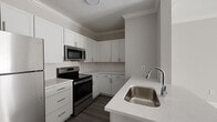Located at 2430 Cheshire Bridge Rd NE in Atlanta, GA, this well-designed one-bedroom, one-bathroom residence offers a clean, modern aesthetic with thoughtful finishes throughout. The open-concept kitchen and living area serves as the heart of the home, featuring light wood-style flooring and crown molding that lend a polished touch. The kitchen is outfitted with white shaker cabinetry, quartz countertops, a subway tile backsplash, and stainless steel appliances including a range, microwave, refrigerator, and dishwasher. A peninsula with an undermount sink provides additional prep space and a natural division between the kitchen and the expansive living area. The living room is bright and open, with light-toned walls and access to French doors that invite natural light and outdoor views. The bedroom is a comfortable retreat with a ceiling fan, a large window overlooking greenery, and ample room for furnishings. A dedicated closet provides practical storage. The bathroom includes a tub-shower combination with white tile surround, a vanity with storage, and dark hardwood-style flooring. Hallways connect the spaces efficiently, contributing to a logical and functional floor plan throughout this well-appointed Atlanta residence.