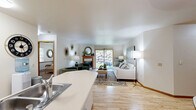 Located at 3021 Maple Valley Dr in Madison, WI, this single-floor, one-bedroom, two-bathroom home offers a well-organized layout across a generously sized floor plan. The entry opens to a dining area with light hardwood flooring, a modern round marble-top table, and a ceiling light fixture, flowing naturally into a fully equipped kitchen featuring warm oak cabinetry, tile flooring, a stainless steel range, dishwasher, and ample counter space. The living room is a comfortable gathering space with hardwood floors, a wood-trimmed fireplace, and a sliding glass door that opens to a patio overlooking a scenic rock garden. A secondary sitting area provides additional lounge space with neutral tones and natural light. The dedicated office area includes recessed lighting and a window, offering a functional workspace. The bedroom features carpet flooring, two windows with outdoor views, and a cozy, well-lit atmosphere. Both bathrooms are finished with oak vanities and tile; one includes a soaking tub. A carpeted multipurpose room with recessed lighting adds flexible utility to the home. Throughout, the space maintains a neutral, warm palette with consistent wood accents and a clean, inviting ambiance.