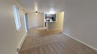 Located at 1206 NW Tahoe Ln in Silverdale, Washington, this single-floor residence offers a well-organized and functional layout designed for comfortable everyday living. The open-concept living and dining area is finished with plush wall-to-wall carpeting that adds warmth underfoot, while a ceiling fan overhead provides year-round comfort. Natural light filters in through a sliding glass door, enhancing the bright and airy feel of the main living space. Baseboard heating runs along the perimeter walls, ensuring efficient climate control throughout the cooler Pacific Northwest seasons. The kitchen is positioned at the heart of the home, defined by a raised peninsula counter that creates a natural division between the cooking and living areas while maintaining an open sightline. Dark espresso-toned cabinetry provides ample storage, and the kitchen is equipped with black appliances including a refrigerator and range. The flooring in the kitchen transitions to a smooth, easy-care hardwood-style surface, offering a practical contrast to the carpeted living area. Clean, neutral wall tones throughout the space create a versatile backdrop that suits a variety of interior styles. The overall layout is efficient, cohesive, and move-in ready.