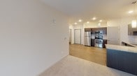 Unit 311 is a thoughtfully designed single-floor residence offering a cohesive blend of contemporary finishes and functional living spaces. The kitchen serves as a central highlight, featuring dark espresso cabinetry, granite countertops, a white subway tile backsplash, and a full suite of stainless steel appliances including a refrigerator, electric range, microwave, and dishwasher. Wood-look flooring grounds the kitchen and flows into the adjacent living area, which transitions to plush carpeting. A dedicated pantry with built-in wire shelving provides additional storage directly off the kitchen.

The living space is generously proportioned, with a sliding glass door leading to a private balcony offering exterior views. Bedrooms are carpeted and receive natural light through large windows with outdoor views. Ceiling fans add comfort to the bedroom areas, while exposed ductwork contributes an industrial accent.

The bathroom is well-appointed with a double-sink vanity, dark wood cabinetry, granite countertops, and modern light fixtures above a wide mirror. A dedicated laundry room with a full-size washer and dryer and overhead wire shelving adds everyday convenience. A spacious walk-in closet with multi-level wire shelving completes this well-organized unit.