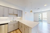 Located at 90 Ocean Ave in Revere, MA, this thoughtfully designed one-bedroom, one-bathroom residence offers a clean, modern aesthetic throughout its efficiently laid-out single floor. Light hardwood flooring flows seamlessly from room to room, creating a bright and cohesive feel.

The open-concept kitchen and living area serves as the heart of the unit. The kitchen is outfitted with grey shaker-style cabinetry with gold hardware, quartz countertops, a classic white subway tile backsplash, and a full suite of stainless steel appliances including a range, microwave, dishwasher, and refrigerator. A peninsula provides additional counter space and defines the boundary between the kitchen and living area. Pendant lighting above the peninsula adds a warm, stylish touch. The living area features a sliding glass door that opens to a private balcony, allowing ample natural light to fill the space.

The bedroom is a comfortable, well-proportioned room with a large window offering outdoor views, recessed lighting, and access to a dedicated closet with a rod and shelving. The bathroom features white hexagonal tile flooring and brass hardware accents, contributing to the unit's modern yet refined character. The overall ambiance is bright, clean, and move-in ready.