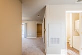 This single-floor residence offers a thoughtfully arranged layout that balances open communal areas with private living spaces. The living area is generously sized, featuring plush carpeting, a ceiling fan with integrated lighting, and large windows fitted with blinds that allow ample natural light to fill the room. A built-in nook adds a subtle architectural detail to the space.

The kitchen is efficiently designed with crisp white cabinetry extending to the ceiling for maximum storage, light granite-style countertops, hardwood-style flooring, and stainless steel appliances including a dishwasher and range. A window above the sink brings in additional natural light, creating a bright and functional workspace.

The bedroom is a comfortable, carpeted room with neutral warm-toned walls and a window with blinds providing natural light and privacy. The room offers a calm and restful atmosphere well-suited for relaxation.

The bathroom features hardwood-style flooring, white cabinetry with granite-style countertops, an undermount sink, a mirrored vanity, and a bathtub with a shower curtain rod. The space is clean and bright.

A central hallway connects the rooms and includes a utility panel and HVAC access built into the wall, keeping mechanical systems neatly integrated. Throughout the residence, neutral tones, consistent flooring choices, and practical finishes create a cohesive and move-in-ready environment.
