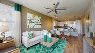 Located at 5671 Mauna Loa Blvd in Sarasota, Florida, this single-story residence offers a thoughtfully designed open-concept floor plan that seamlessly connects the main living areas. The kitchen is a standout feature, outfitted with crisp white cabinetry, a decorative tile backsplash, stainless steel appliances including a large refrigerator, quartz countertops, and a central island with pendant lighting — ideal for both cooking and casual dining. Track lighting and wood-look flooring throughout the main living areas add to the modern aesthetic. The living room is bright and welcoming, with multiple windows that invite natural light, a ceiling fan, and direct sightlines to the kitchen and dining area, creating a cohesive and functional common space. Two well-proportioned bedrooms each feature plush carpeting, ceiling fans, and windows with outdoor views. The primary bedroom includes access to a walk-in closet with wire shelving. The bathroom is clean and contemporary, featuring a sliding glass-enclosed shower, a dual-sink vanity with stone countertops, and tile flooring. A dedicated laundry room houses a full-size washer and dryer with overhead shelving, adding everyday convenience to this well-appointed Sarasota residence.