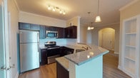 This single-floor residence on Warrick Trail offers a thoughtfully designed open-concept layout that connects the living and kitchen areas seamlessly. The kitchen serves as a central highlight, showcasing rich dark espresso cabinetry, granite countertops, and a classic white subway tile backsplash. Stainless steel appliances—including a refrigerator, range, microwave, and dishwasher—complement the space, while pendant lighting and a peninsula with bar seating add both function and style. Crown molding and arched architectural details throughout lend an elegant finishing touch.

The open living area features warm hardwood-style flooring and flows naturally from the kitchen, creating a cohesive gathering space. Bedrooms are carpeted for comfort, each equipped with ceiling fans and windows fitted with horizontal blinds that allow ample natural light. One bedroom features a striking arched window that adds architectural character.

The bathrooms are finished with dark cabinetry and granite-topped vanities, maintaining a consistent design language throughout. One bathroom includes a tub-shower combination, while another features a walk-in shower configuration. Overall, the residence presents a clean, modern aesthetic with quality finishes in every room.