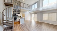 This thoughtfully designed two-bedroom, two-bathroom home spans two floors, offering a generous and functional layout. The main level immediately impresses with soaring double-height ceilings that flood the open living area with natural light through expansive clerestory windows. Light-toned hardwood-style flooring runs throughout, complementing the clean, modern aesthetic. A distinctive spiral staircase adds an architectural focal point while connecting the two levels seamlessly.

The open-concept kitchen is well-appointed with white shaker cabinetry, light quartz countertops, a mosaic tile backsplash, stainless steel appliances including a gas range, built-in microwave, and a French door refrigerator, along with a deep double-basin sink. A peninsula counter provides additional workspace and defines the kitchen's boundary with the living area.

Both bathrooms feature full tub-and-shower combinations finished with floor-to-ceiling large-format gray marble-look tile and brushed nickel fixtures, creating a clean and refined feel. The bedrooms are comfortably sized, each featuring wood-style flooring, neutral gray walls, and windows with roller shades. The primary bedroom includes a built-in closet with mirrored sliding doors and organized shelving. The upper floor provides a more intimate retreat, while the expansive main level offers ample room for living and entertaining.