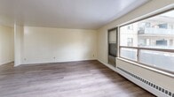 Located at 275 Wentworth St W in Oshawa, Ontario, this one-bedroom, one-bathroom unit offers a practical and well-organized layout across a single floor. Light-toned laminate flooring runs throughout the space, lending a clean and cohesive look to every room.

The open living, dining, and kitchen area forms the heart of the unit. The living area is generously proportioned, bathed in natural light from a large window that also offers views to the exterior. A baseboard heating unit sits beneath the window, ensuring year-round comfort. The walls are finished in a warm neutral tone, creating a bright and airy atmosphere.

The bedroom is a comfortable, well-sized room with the same light laminate flooring and crisp white walls, providing a calm and restful environment. The kitchen is accessible from the main living area and features built-in cabinetry and appliances.

The bathroom is finished with a full-sized soaking tub and shower combination, accented by a mosaic tile border detail along the top of the surround, adding a subtle decorative touch to the otherwise clean, white finish.

Overall, the unit presents a functional and tidy living space with consistent finishes throughout, making it a straightforward and practical home in the heart of Oshawa.