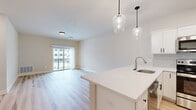 This well-appointed 2-bedroom, 1-bathroom residence at 28 Everett Rd Ext in Albany, NY offers a thoughtfully designed single-floor layout with modern finishes throughout. The open-concept kitchen and living area serves as the heart of the home, featuring light hardwood flooring, a large kitchen island with white quartz countertops, a stainless steel undermount sink, and elegant pendant lighting. The kitchen is outfitted with white shaker cabinetry, a subway tile backsplash, and a full suite of stainless steel appliances. A sliding glass door in the living area opens to a private balcony, filling the space with natural light. Both bedrooms are carpeted for comfort, with the generously sized primary bedroom offering ample space and access to a walk-in closet equipped with wire shelving. The full bathroom is finished with a dual-sink vanity featuring gray shaker cabinets and black hardware, a large mirror, marble-look tile flooring, and a walk-in shower. A dedicated laundry room with full-size washer and dryer hookups adds everyday convenience. Clean neutral tones and consistent modern detailing create a cohesive, contemporary ambiance throughout the entire residence.