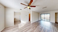 Located at 5565 Connie Jean Rd in Jacksonville, FL, this single-story home offers four bedrooms and one bathroom within a compact, efficiently designed floor plan. Light-toned wood-look flooring runs throughout the home, creating a cohesive and easy-to-maintain interior. The open living room features a ceiling fan and a sliding glass door that fills the space with natural light and provides direct access to the outdoor area. A textured ceiling adds a classic touch to the living space. The kitchen is laid out in a practical galley style, featuring wooden cabinetry, light stone-look countertops, a stainless steel sink with a window above it, and white appliances including a range and refrigerator. Louvered closet doors and an adjacent open storage area provide added utility. Each of the four bedrooms is finished with the same wood-look flooring and includes closet space with wire shelving. The primary bedroom features a large sliding glass door offering outdoor views and additional natural light. The single full bathroom is cleanly appointed with a vanity, mirror, and a tub-shower combination unit.
