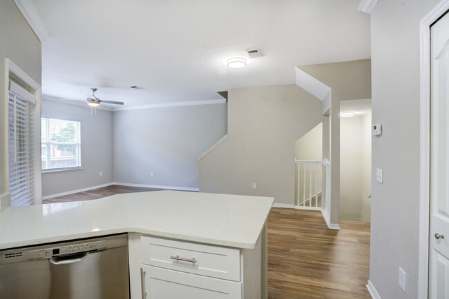 Image of a kitchen with a view of the living room with wood-style plank style floors. - Amara at Metro West