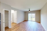 This well-designed 3-bedroom, 2-bathroom single-floor residence in Wentzville, Missouri offers a thoughtful layout with a clean, modern aesthetic. The open-concept kitchen and living area serves as the heart of the home, featuring warm wood-tone cabinetry, granite countertops, stainless steel appliances including a dishwasher, range, microwave, and refrigerator, and light wood-look flooring that extends throughout the main living spaces. Sliding glass doors in the living area open to a private balcony, filling the room with natural light and providing outdoor views. A ceiling fan with a contemporary fixture accents the living space. The bedrooms offer plush carpeting, ceiling fans, and generous closet space, including a spacious walk-in closet with wire shelving in the primary suite. Secondary bedrooms feature sliding-door closets. The two bathrooms are finished with wood-look flooring, clean white fixtures, and warm wood vanities. Additional functional spaces include a pantry, dedicated laundry room, utility room, and a central hallway connecting all areas. With five closets throughout, storage is a standout feature of this well-appointed home.