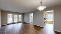 Located at 910 Saint Andrews Drive in Murfreesboro, Tennessee, this 2-bedroom, 2-bathroom single-story home offers a well-organized layout designed for comfortable everyday living. The open living area is finished with rich wood-look flooring and neutral gray walls, creating a clean, welcoming atmosphere. A pendant light fixture anchors the space, while French doors flood the room with natural light and provide outdoor access. The kitchen sits adjacent to the living area and features warm oak cabinetry, dark granite-style countertops, a dishwasher, and a large window that brings in additional natural light. Both bedrooms are carpeted for comfort, each equipped with a ceiling fan or lighting fixture and a closet with sliding or hinged doors. The primary bedroom offers a generous footprint with ample closet space. The two bathrooms are consistent in their finishes, featuring wood-look tile flooring, oak vanities with dark countertops, tub-shower combinations with white tile surrounds, and windows that allow natural light. A hallway connects the main living spaces to the bedrooms and bathrooms, contributing to an efficient and practical floor plan throughout this well-appointed Murfreesboro home.