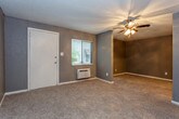 This single-floor unit offers a practical and comfortable layout designed for efficient everyday living. The open living area is finished with plush carpeting and neutral gray walls, creating a calm and cohesive atmosphere. A ceiling fan with a light fixture adds both comfort and functionality, while multiple windows dressed with horizontal blinds allow natural light to fill the space and offer views of the surrounding greenery. A private exterior door provides convenient access directly from the living area.

The kitchen is thoughtfully arranged with warm-toned wood cabinetry, dark granite-style countertops, and wood-look vinyl flooring that adds a touch of warmth and is easy to maintain. White appliances, including a refrigerator, gas range, and overhead ventilation hood, complete the kitchen's functional setup.

The bathroom is clean and well-appointed, featuring a full soaking tub with a shower surround, a wood-vanity with a granite-style countertop, an integrated sink, and a mirror. The wood-look flooring continues here, tying the space together with a consistent design language. Textured gray walls throughout the unit add subtle visual interest and character. Overall, the space presents a straightforward, move-in-ready layout with practical finishes suited for comfortable daily living.