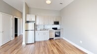 Located at 30 Market St SW in Concord, North Carolina, this thoughtfully designed single-floor unit offers a practical and modern layout. The open-concept kitchen and living area serves as the heart of the space, featuring warm wood-look flooring, soft gray walls, and clean white trim that create a bright, cohesive aesthetic. The kitchen is outfitted with light wood cabinetry, granite-look countertops, a stainless steel refrigerator, dishwasher, and range, providing a fully functional cooking space. The living area is bathed in natural light through a large sliding glass door that opens to a private balcony, offering outdoor views of the surrounding Concord streetscape. A ceiling fan overhead adds both comfort and style to the living space. A dedicated closet provides convenient storage, while the bathroom features wood-look flooring, a full tub-shower combination with clean white tile surround, and a clean, minimal design. The unit's consistent use of neutral tones, modern fixtures, and durable flooring throughout gives it a fresh, contemporary feel well-suited for efficient urban living in downtown Concord.