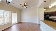 Located at 1406 Shady Ln in Burkburnett, TX, this single-story 2-bedroom, 2-bathroom home offers a well-designed layout with comfortable living spaces throughout. The open-concept kitchen is a standout feature, equipped with rich dark cabinetry, granite countertops, a granite-topped island with pendant lighting, and black appliances including a refrigerator, range, dishwasher, and built-in microwave. An elegant arched passageway connects the kitchen area to the living room, which features hardwood-style flooring, crown molding, a ceiling fan, and a sliding glass door that invites natural light. Both bedrooms are carpeted and include ceiling fans and windows with natural light; the primary bedroom is a generous size with its own en-suite bathroom featuring a double-sink granite vanity, a walk-in shower, and hardwood-style flooring. The second bathroom includes a tub-shower combination with tile surround. The home also includes two hallways, two closets with wire shelving, and a dedicated laundry room with washer and dryer hookups. The warm, neutral color palette and consistent finishes throughout give the home a cohesive and inviting ambiance.