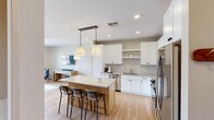 Located on North Scottsdale Road in Scottsdale, AZ, this thoughtfully designed one-bedroom, one-bathroom residence offers a functional and contemporary single-floor layout. Light wood flooring flows throughout, creating a warm, cohesive aesthetic.

The open-concept kitchen is a standout feature, equipped with stainless steel appliances including a gas range, refrigerator, dishwasher, and microwave. White shaker cabinetry with matte black hardware pairs with a subway tile backsplash and quartz countertops. A central island with pendant lighting provides additional prep space and casual seating.

The living area is bright and open, featuring a ceiling fan, access to an outdoor balcony, and natural light from large windows. The bedroom is generously sized, appointed with a ceiling fan and expansive windows offering views of the surrounding Scottsdale landscape, including glimpses of the desert mountains.

The bathroom features a glass-enclosed walk-in shower with marble-style tile surround, a single vanity, and built-in wall shelving for added storage. The walk-in closet includes built-in shelving and dual hanging rods. A dedicated in-unit laundry room houses a full-size front-loading washer and dryer, completing this well-appointed Scottsdale residence.