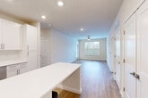 Located on Pine Place in La Plata, Maryland, this well-appointed 3-bedroom, 2-bathroom single-floor home offers a clean, modern aesthetic throughout. The open-concept living area seamlessly connects the kitchen, dining, and living spaces, creating a bright and airy atmosphere enhanced by recessed lighting and a ceiling fan. Large windows allow natural light to fill the living room, which features warm wood-look hard surface flooring and a neutral color palette.

The kitchen is a standout feature, showcasing crisp white shaker-style cabinetry, a large center island with white quartz countertops, stainless steel appliances including a refrigerator, range, microwave, and dishwasher, and open shelving for added functionality. The space flows effortlessly into the dining and living areas, making it ideal for everyday living and entertaining.

The three bedrooms are comfortably sized, with the primary bedroom offering generous proportions and plush carpeting. Impressively, the home includes seven closets throughout, providing exceptional storage. The bathrooms are finished with white vanities, quartz countertops, wood-look flooring, and clean, modern fixtures. A central hallway connects all rooms, maintaining a practical and cohesive floor plan throughout this thoughtfully designed home.