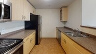 Located at 160 Pleasant St in Malden, Massachusetts, this well-appointed residential unit offers a thoughtfully designed single-floor layout with an open, airy feel throughout. The living area is generously proportioned, featuring plush wall-to-wall carpeting and large corner windows that flood the space with natural light while offering elevated views of the surrounding Malden cityscape. A second carpeted bedroom also benefits from oversized windows, maintaining the unit's bright and open character.

The galley-style kitchen is efficiently laid out with light maple cabinetry, granite-toned countertops, and a full suite of stainless steel appliances including a range, microwave, dishwasher, and refrigerator. Durable tile flooring completes the kitchen area. An entry corridor connects the kitchen seamlessly to the main living space, providing a practical and organized flow.

The unit includes two full bathrooms. The primary bathroom features a granite-topped vanity with light maple cabinetry, a large mirror, and a window offering natural light. The second bathroom mirrors this aesthetic with a similarly styled vanity and a soaking tub. Neutral warm tones, clean lines, and consistent finishes throughout lend the space a cohesive and functional character well-suited for comfortable urban living.