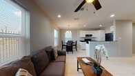 This single-floor unit in Mercedes, Texas, presents a well-designed, open-concept layout that seamlessly connects the living, dining, and kitchen areas. Large windows throughout admit generous natural light, complemented by recessed lighting and ceiling fans that enhance the bright, airy atmosphere.

The living area accommodates comfortable seating and centers around a ceiling fan with lighting. It flows directly into the dining space, which is illuminated by a classic chandelier and flanked by two windows offering outdoor views. The kitchen features white cabinetry, dark granite countertops, black appliances including an electric range and full-size refrigerator, and a peninsula that serves as a natural divider from the living area.

The bedroom is a comfortable retreat with tile flooring, a ceiling fan, and a window that brings in natural light. The bathroom is finished with light-toned walls, tile flooring, a white vanity with countertop, and a full tub-shower combination. Consistent light tile flooring runs throughout the unit, contributing to a cohesive and clean aesthetic across all rooms.